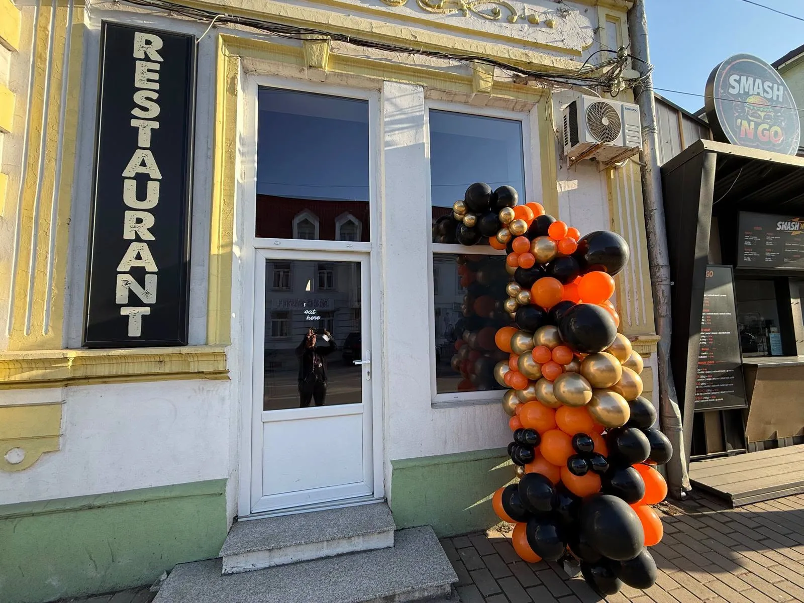 Coloana de baloane portocalii, negre si aurii la intrarea unui restaurant
