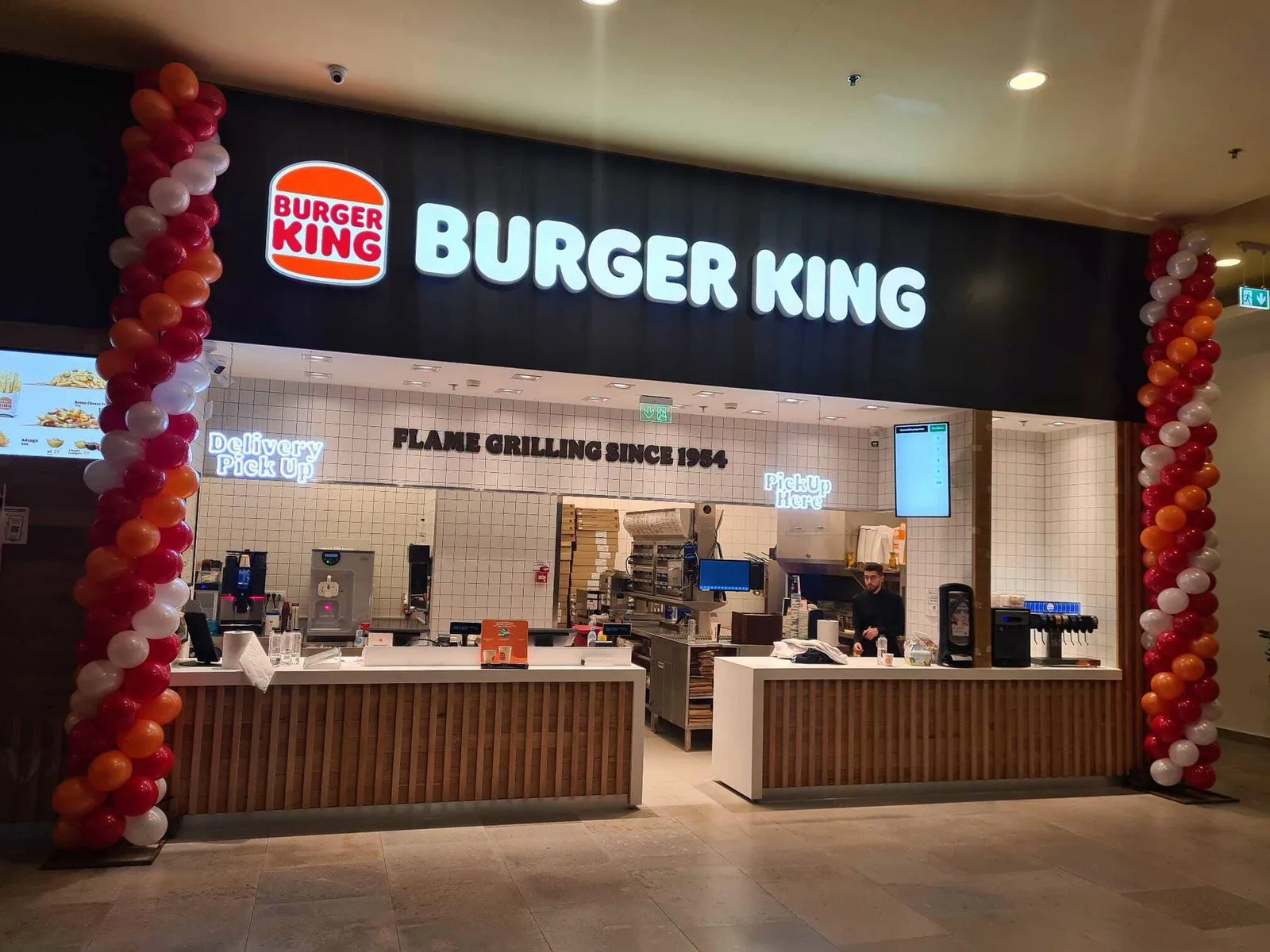 Coloane de baloane rosii, portocalii si albe la deschiderea unui Burger King