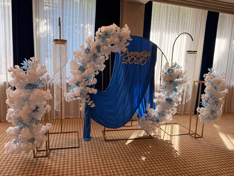Decor de banchet cu arcadă florală albă, drapaj albastru și coloane cu flori