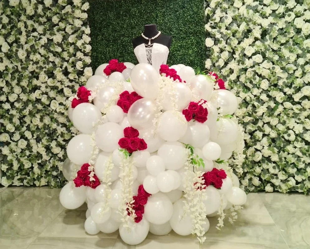 Rochie din baloane albe și flori roșii, expusă pe perete floral
