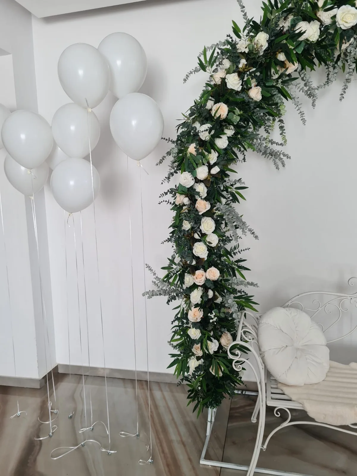 Baloane albe cu heliu asezate langa decorul floral cu trandafiri si eucalipt