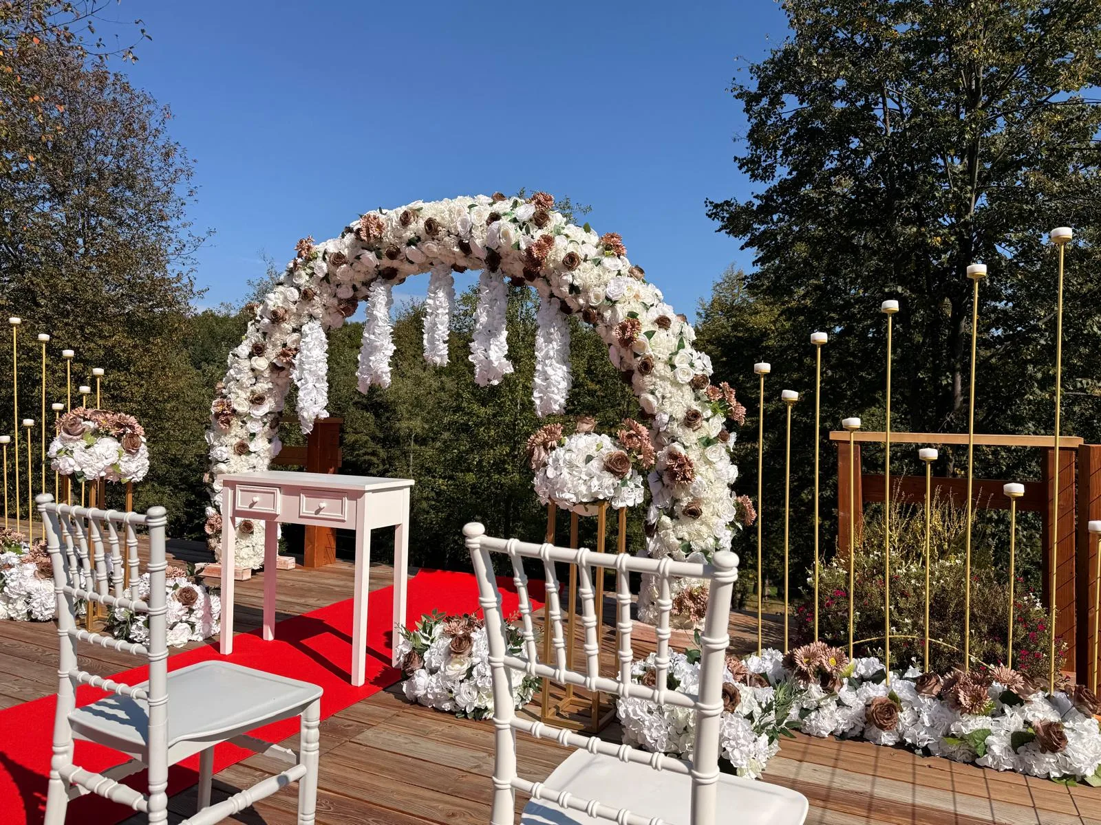 Arcadă florală albă cu scaune Chiavari albe și covor roșu, decor cununie civilă în aer liber