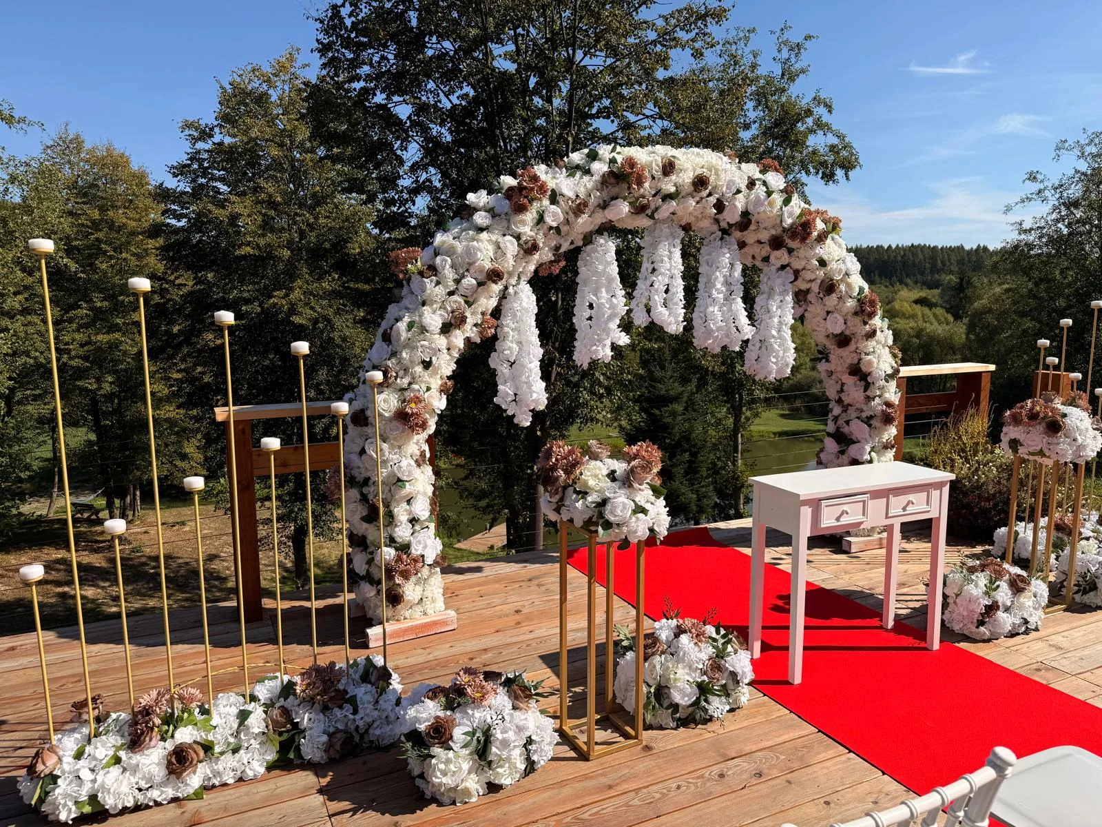 Arcadă florală albă cu stâlpi aurii și flori la bază, decor cununie civilă în aer liber