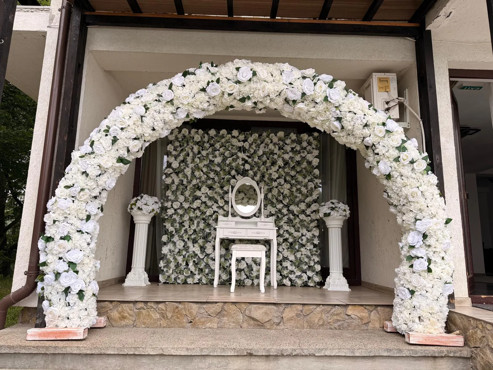 Arcadă cu trandafiri albi și perete floral, măsuță cu oglindă, decor acasă la mireasă