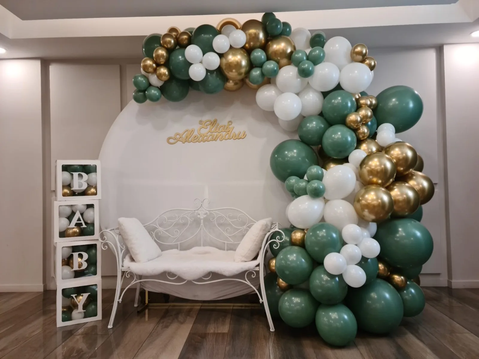 Arcada cu baloane verde, auriu si alb, canapea alba si cutii Baby pentru decor de botez