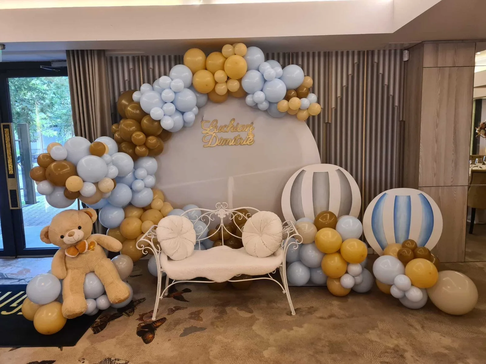 Photocorner de botez bleu cu auriu, nori și montgolfiere decorative, panoul cu numele Luchian Dimitrie