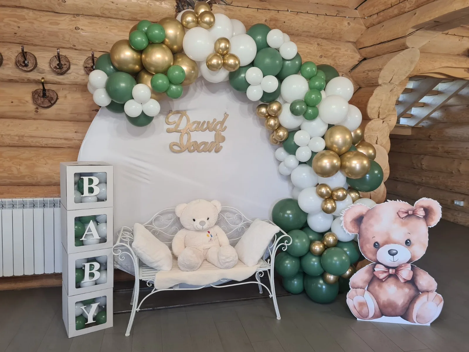 Photocorner de botez verde cu auriu într-o cabană din lemn, ursuleți de pluș, panoul cu numele David Ioan
