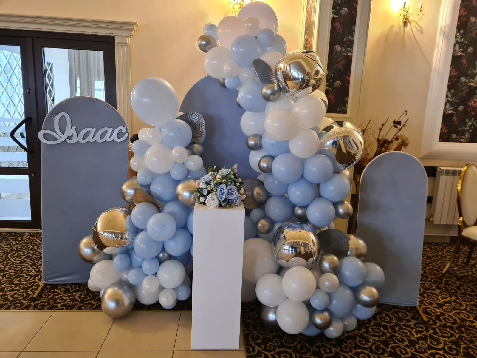 Decor cu coloane de baloane bleu și argintiu, flori și baloane folie argintii, panoul cu numele Isaac