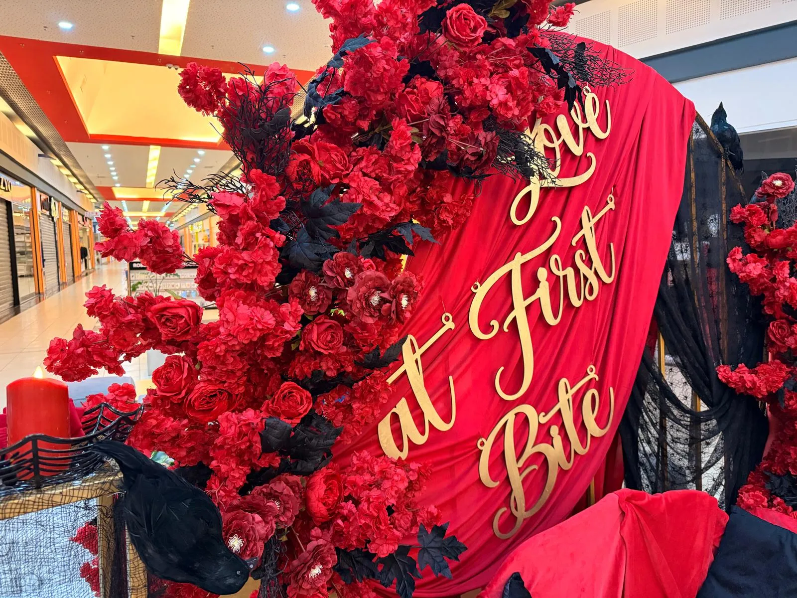 Backdrop rosu cu flori si frunze negre si mesaj Love at First Bite, decor corporate Halloween in mall