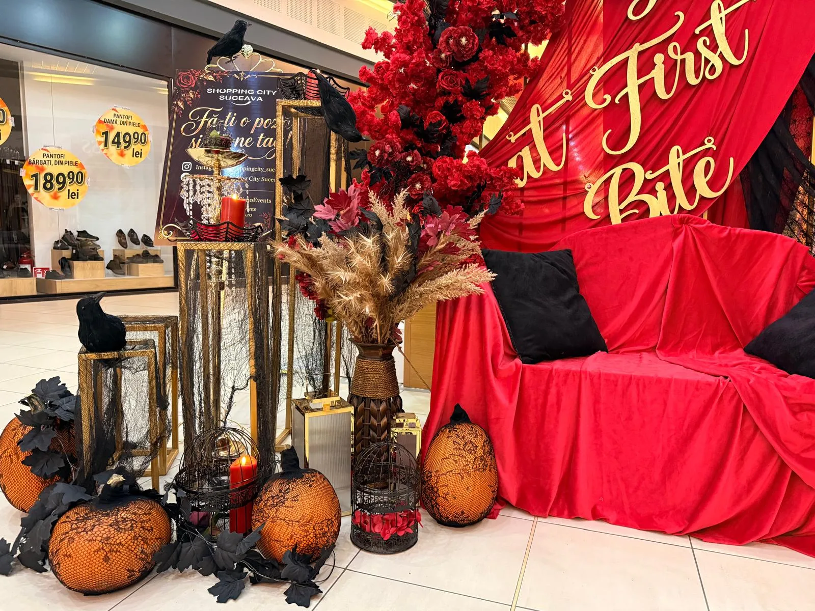 Decor corporate Halloween in mall, canapea rosie cu perne negre, backdrop rosu cu mesaj Love at First Bite