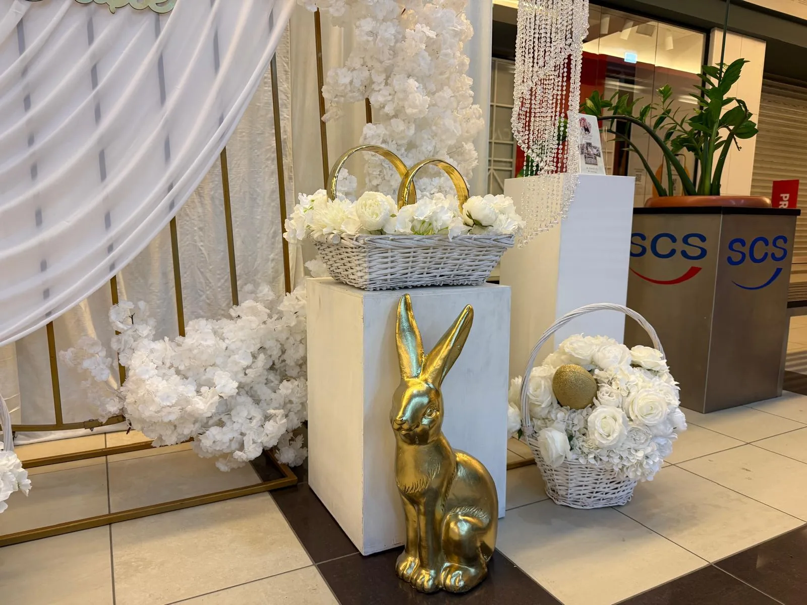 Iepuras auriu langa cosuri impletite cu flori albe, decor corporate de Paste