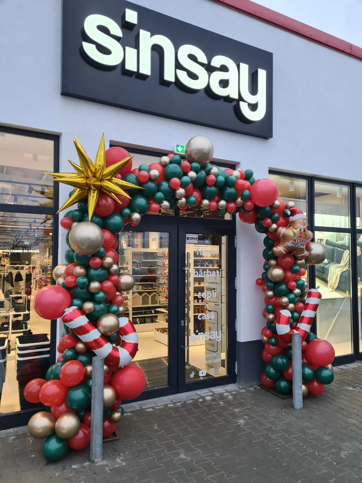 Arcada din baloane rosu-verde-auriu cu stea aurie la intrarea magazinului Sinsay, decor de Craciun