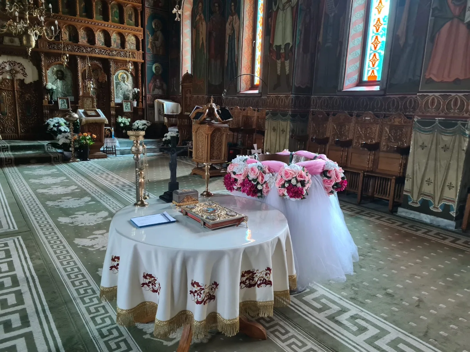 Decor de masă de cristelniță în biserică, cu tul alb și coroniță de flori roz și albe