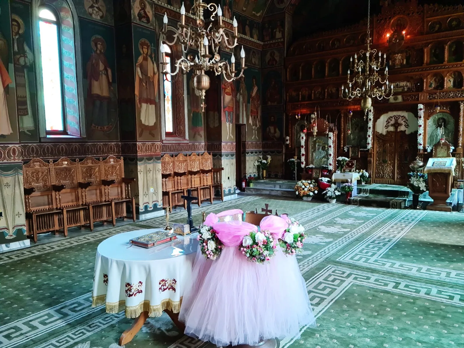 Decor de cristelniță în biserică, cu tul roz pastel și coroniță de flori albe și roz