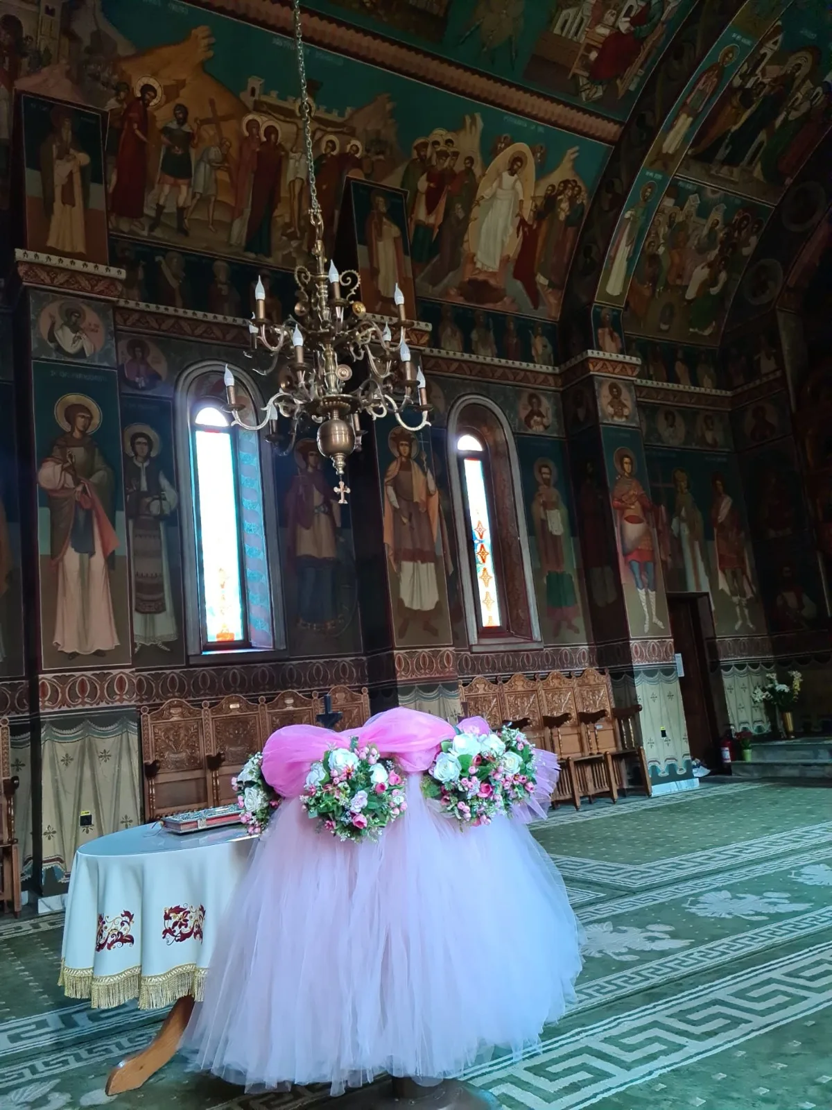 Decor de masă de cristelniță în biserică, cu tul roz pastel și coroniță de flori roz și albe