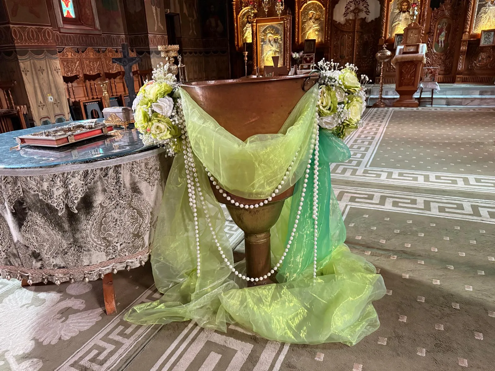 Cupă de cristelniță în biserică, cu tul verde pastel, lanț de perle și flori galbene și albe