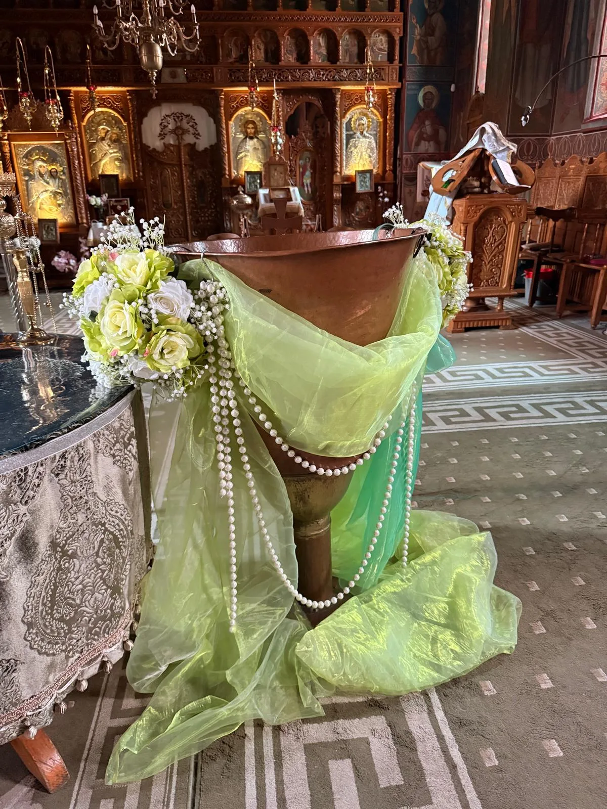 Cupă de cristelniță în biserică, cu tul verde pastel, lanț de perle și aranjament de trandafiri albi și galbeni