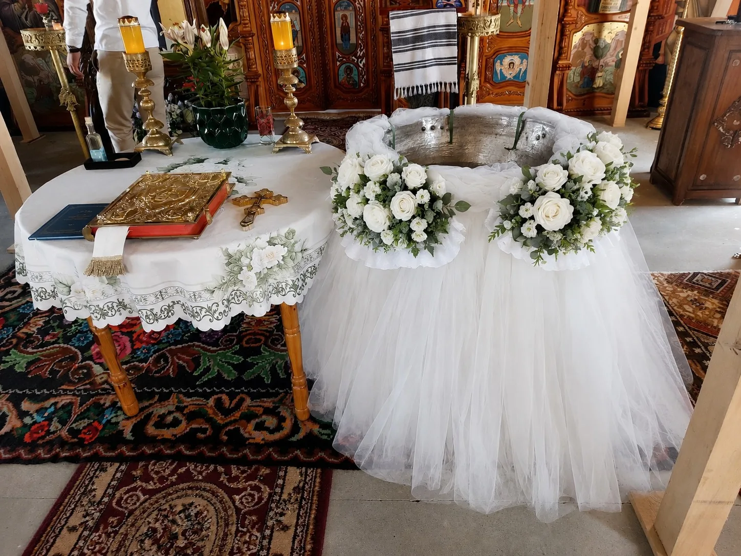Decor de cristelniță în biserică, cu tul alb și coronițe de trandafiri albi