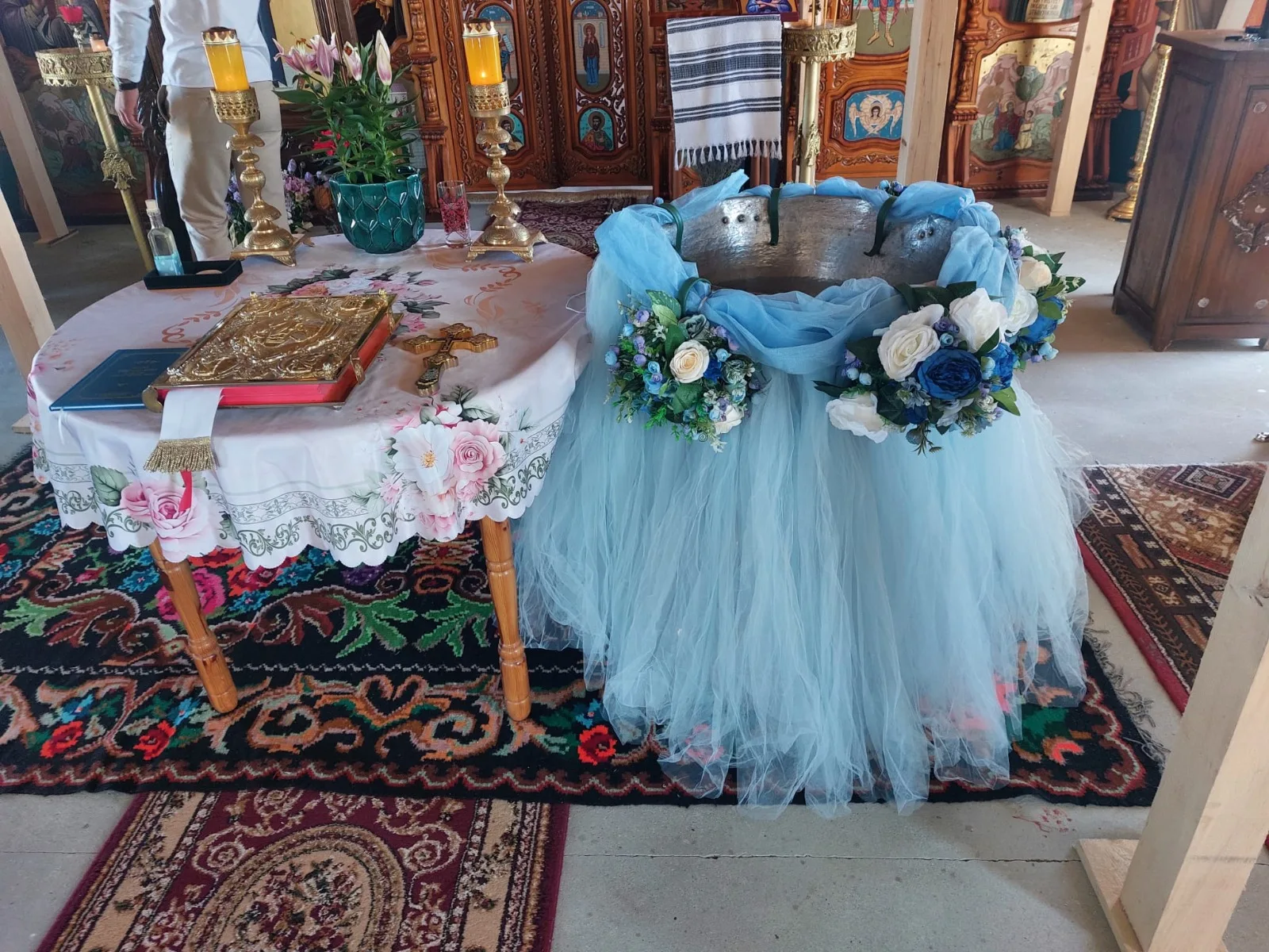 Decor de cristelniță în biserică, cu tul bleu și coronițe de flori albastre și albe