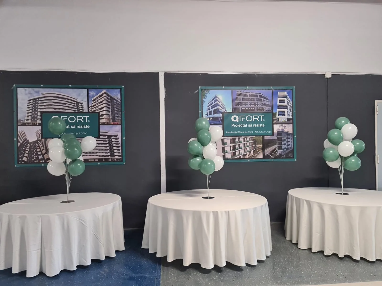 Mese rotunde cu fete albe si aranjamente de baloane verde-alb, in fundal postere QFORT