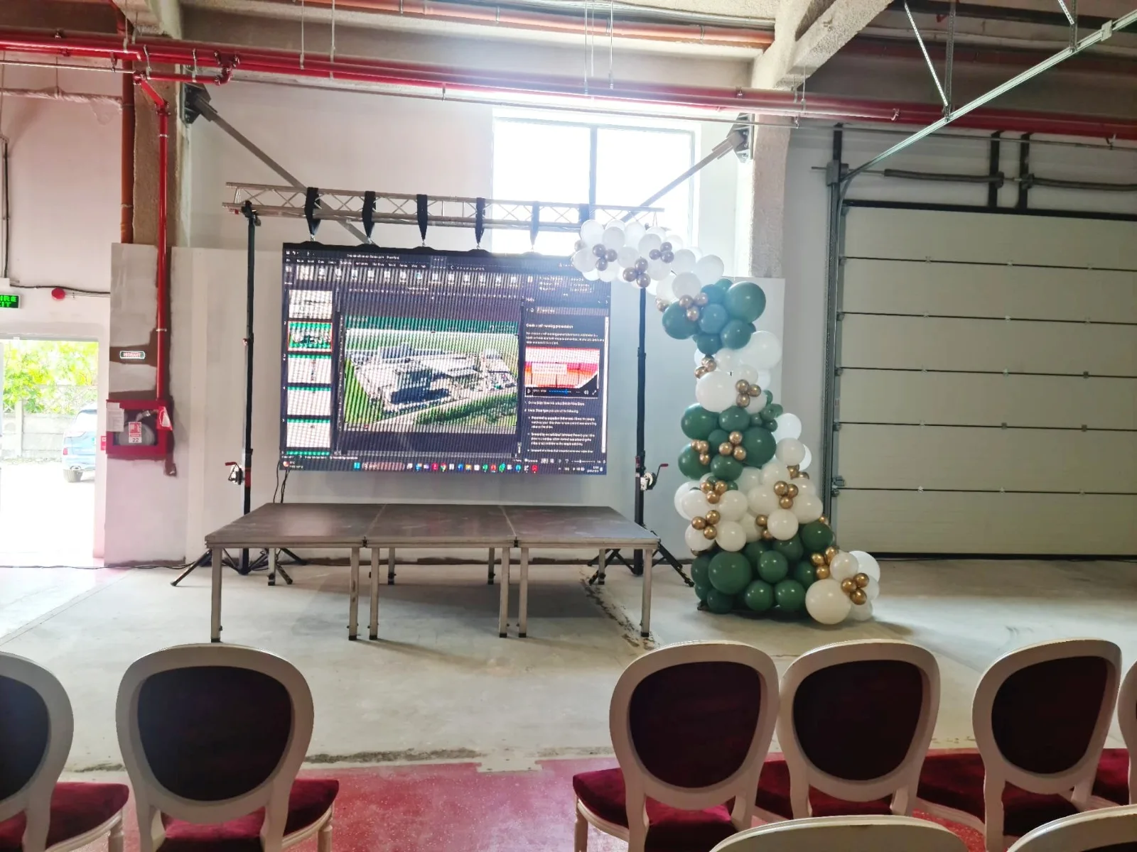 Scena cu ecran de prezentare si arcada de baloane alb-verde la un eveniment corporate QFORT
