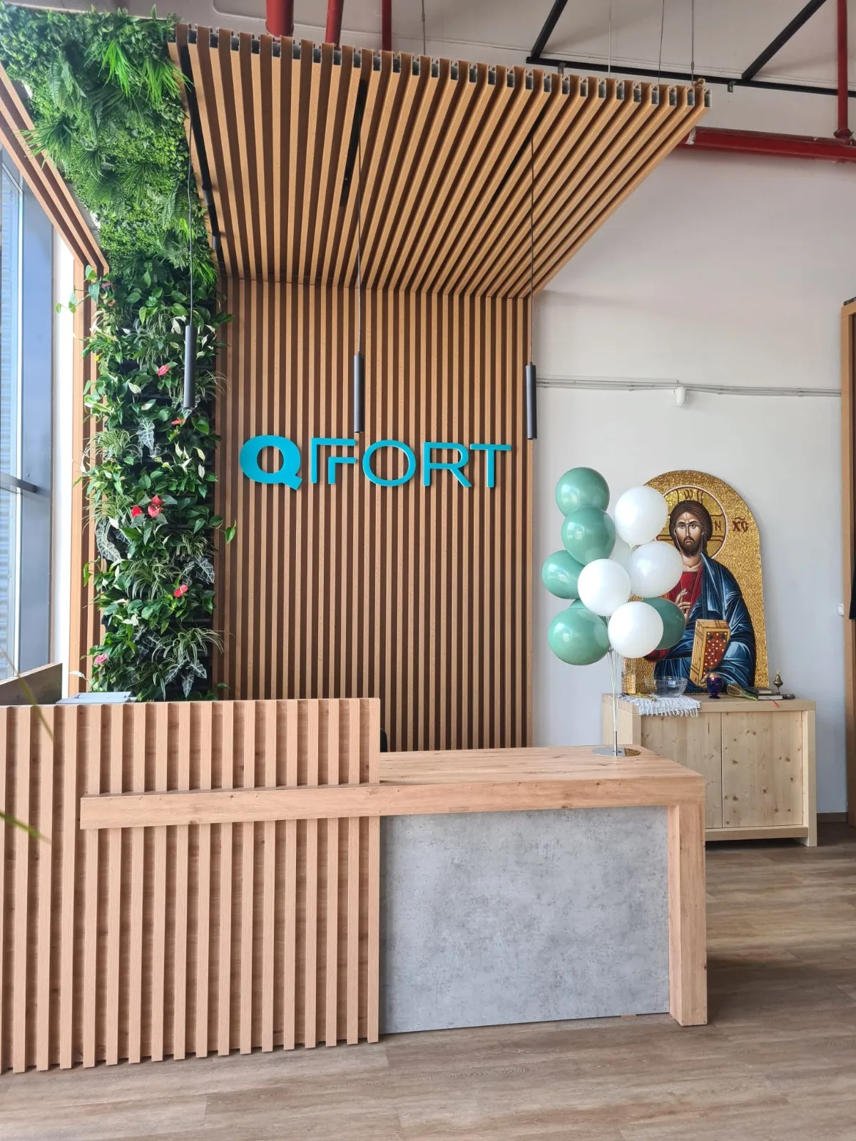 Receptie cu perete verde vertical, logo QFORT si baloane alb-verzi la intrare