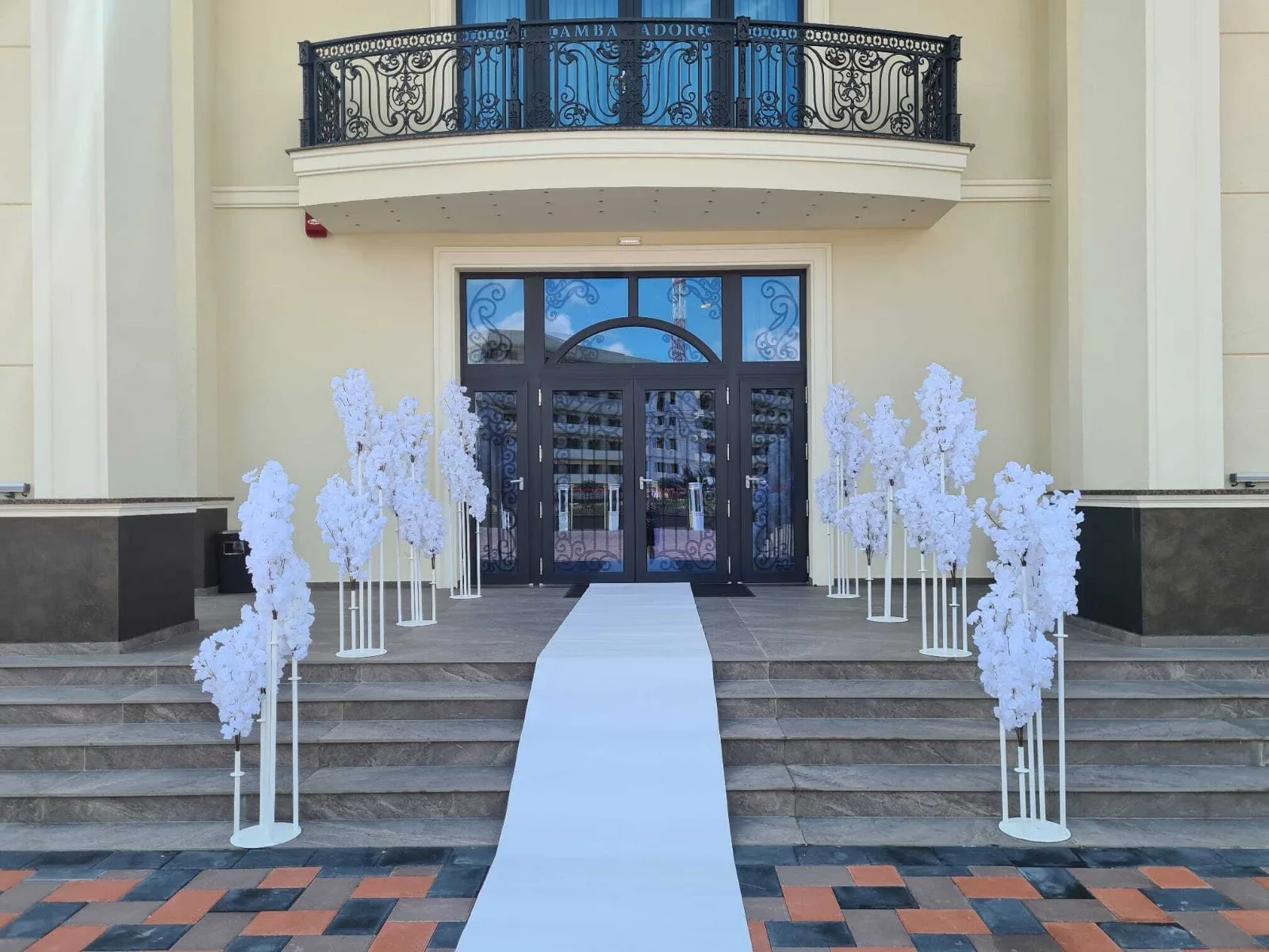 Decor intrare eveniment cu copaci infloriti albi pe scarile cladirii si covor alb pe trepte