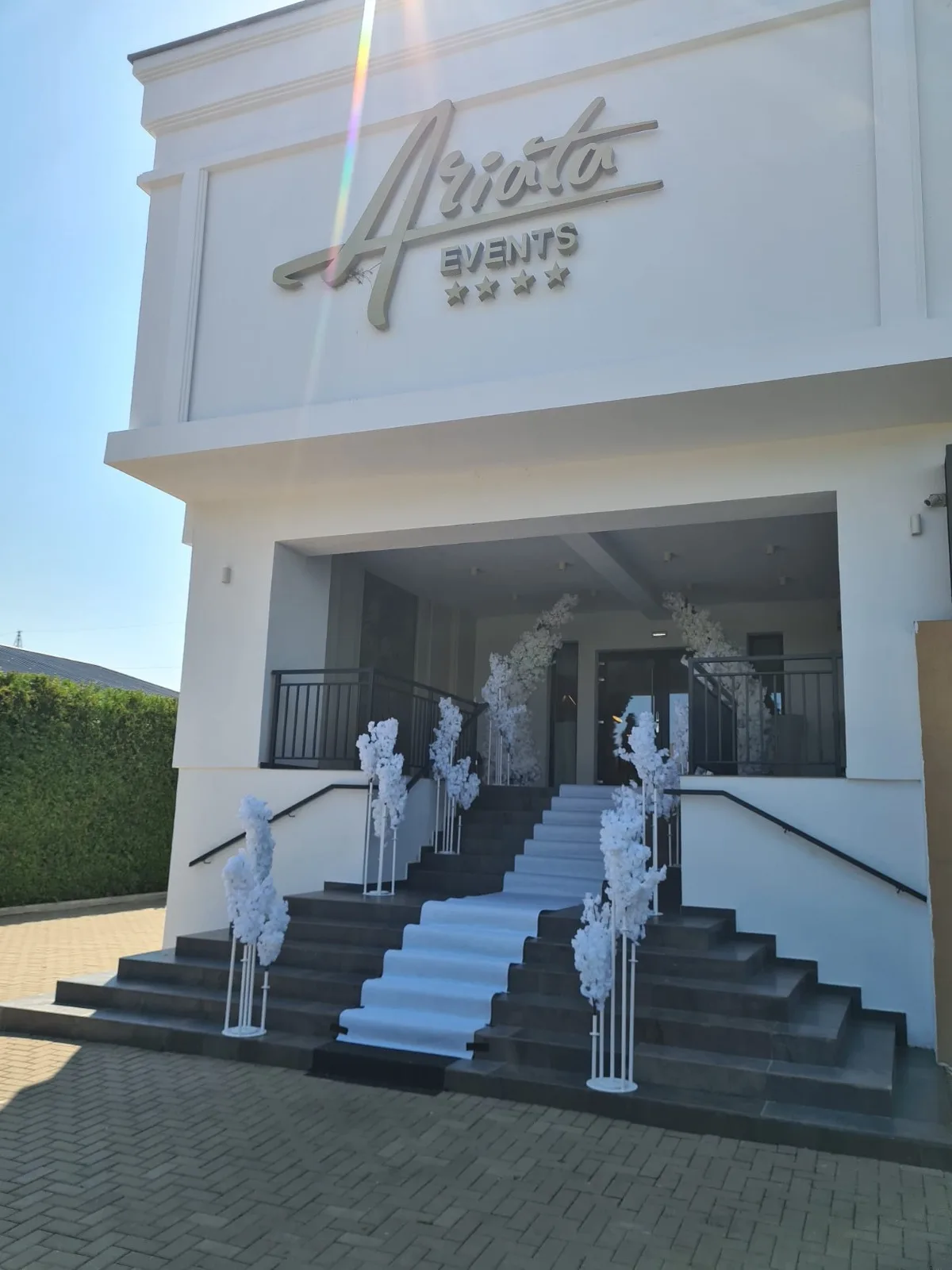 Scari exterioare decorate cu copaci infloriti albi, sub firma cladirii Arioto Events