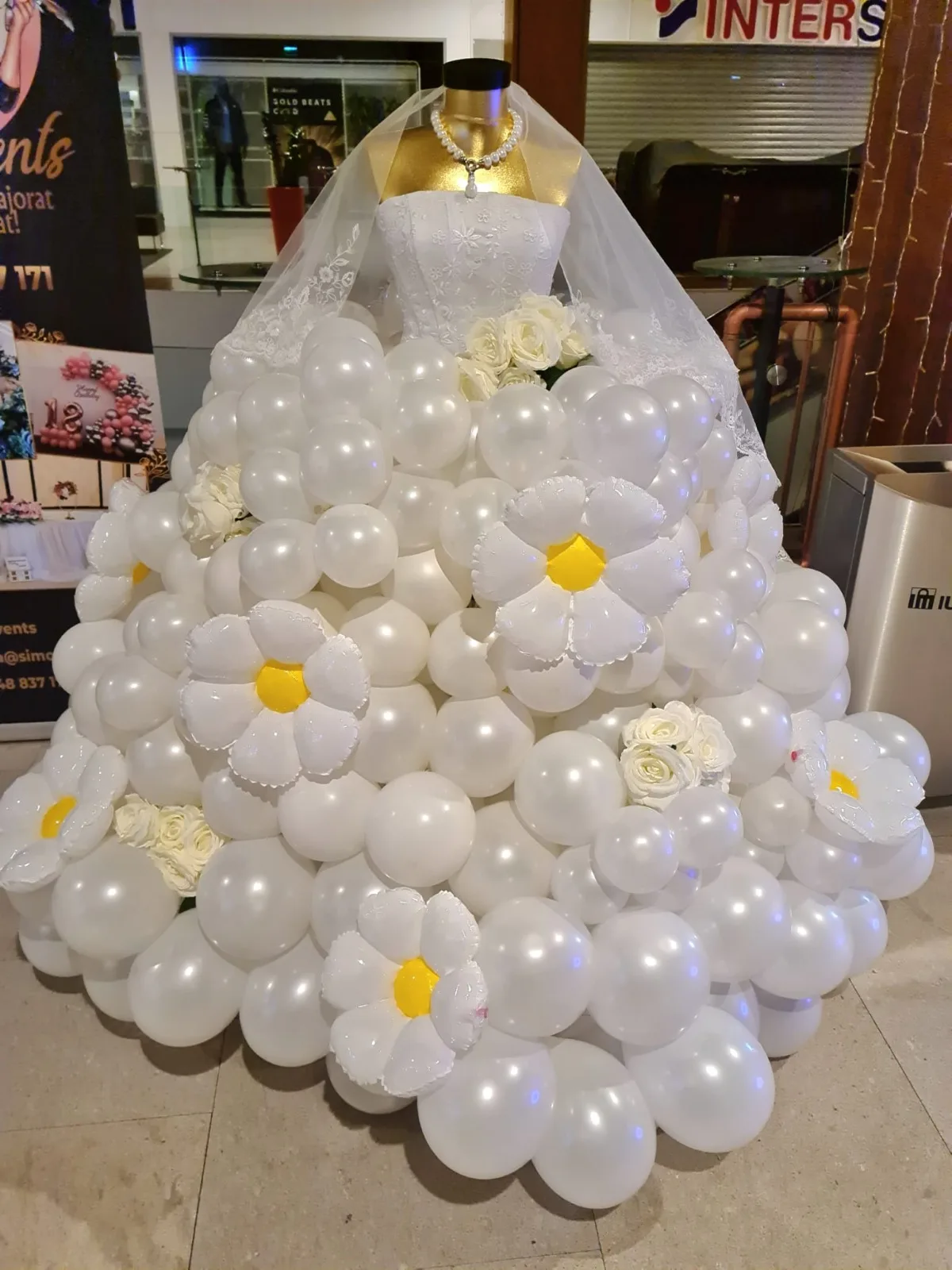 Rochie din baloane albe cu flori tip margaretă, pe manechin, cu voal și colier