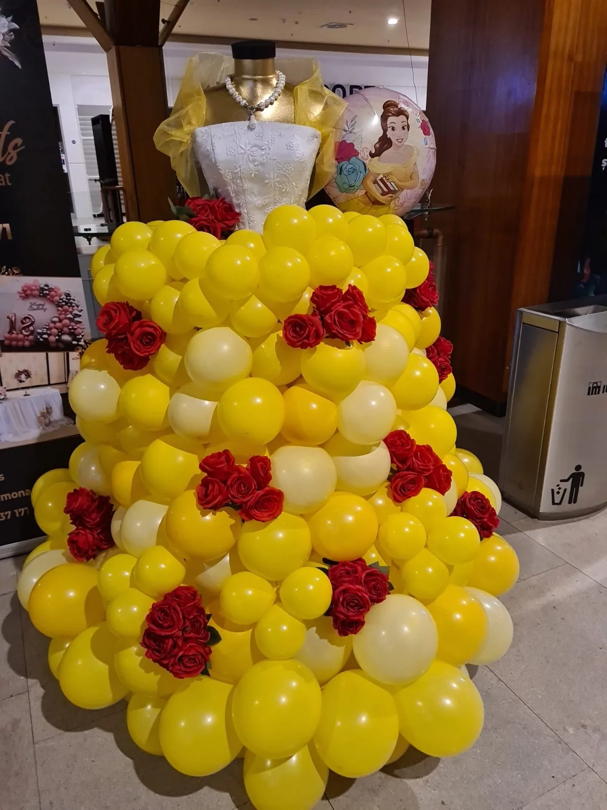 Rochie din baloane galbene cu trandafiri roșii și balon Belle, pe manechin cu bustieră aurie