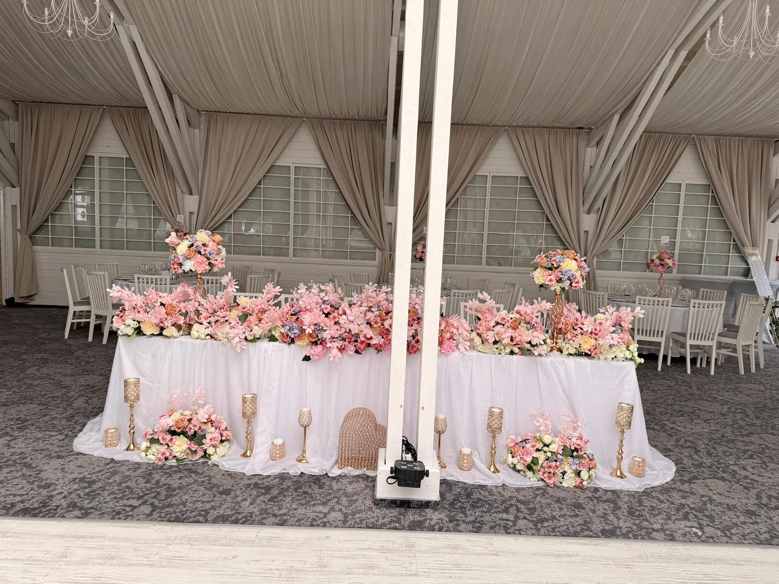 Masa prezidiului cu decor floral roz-pastel pe toată lungimea și sfeșnice aurii cu lumânări, Sala Aldi Gura Humorului