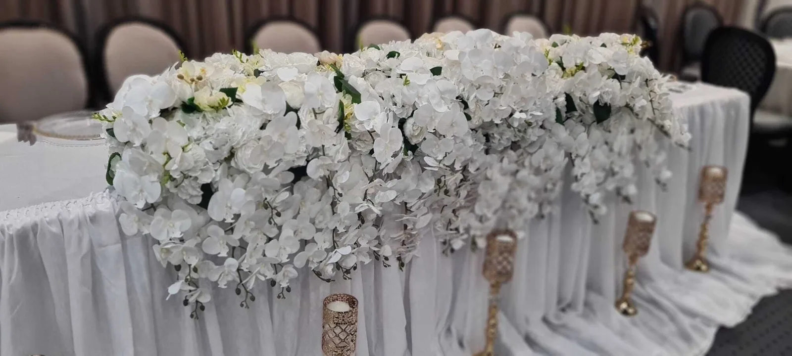 Prezidiu cu aranjament floral alb lung si suporturi aurii cu lumanari