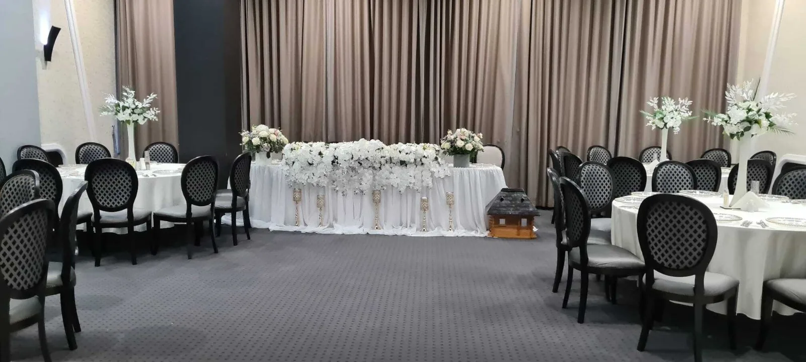 Vedere panoramica a salii cu prezidiu floral si mese rotunde aranjate