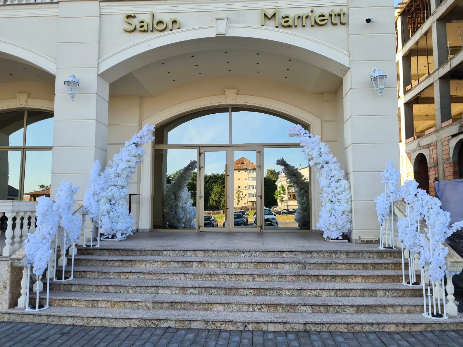 Intrarea Salonului Mariett, cu arcade si copaci decorativi cu flori albe pe trepte