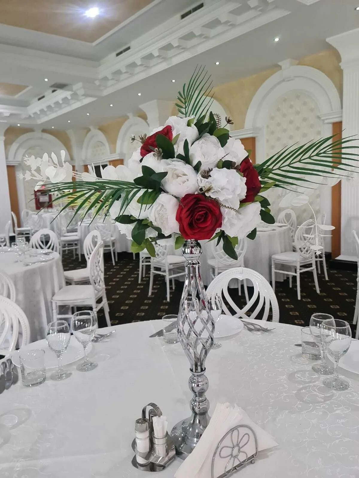 Aranjament floral înalt cu trandafiri roșii și albi pe masă la Sala Zamca