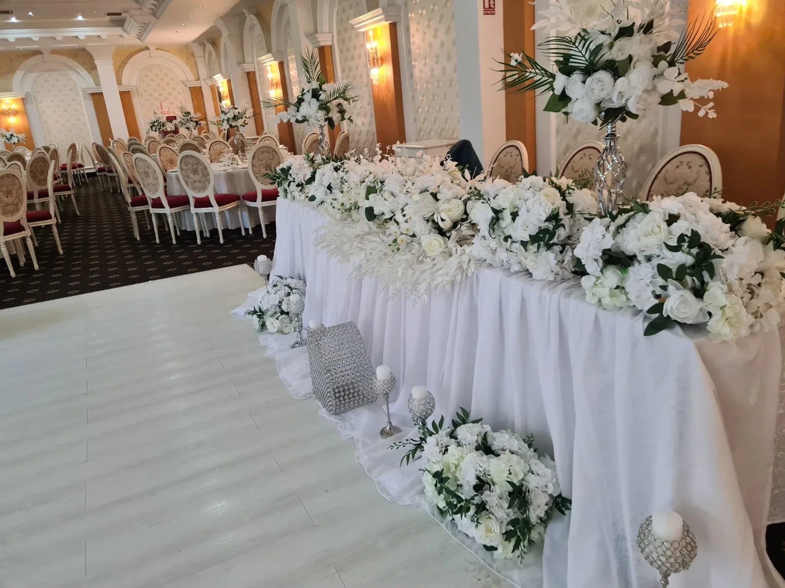 Vedere laterala a prezidiului decorat cu flori albe si aranjamente inalte, Sala Zamca, cu sala de mese in fundal