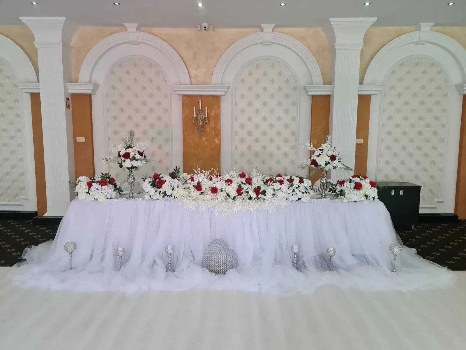 Prezidiu nuntă văzut lateral, tul alb și flori roșii-albe, Sala Zamca