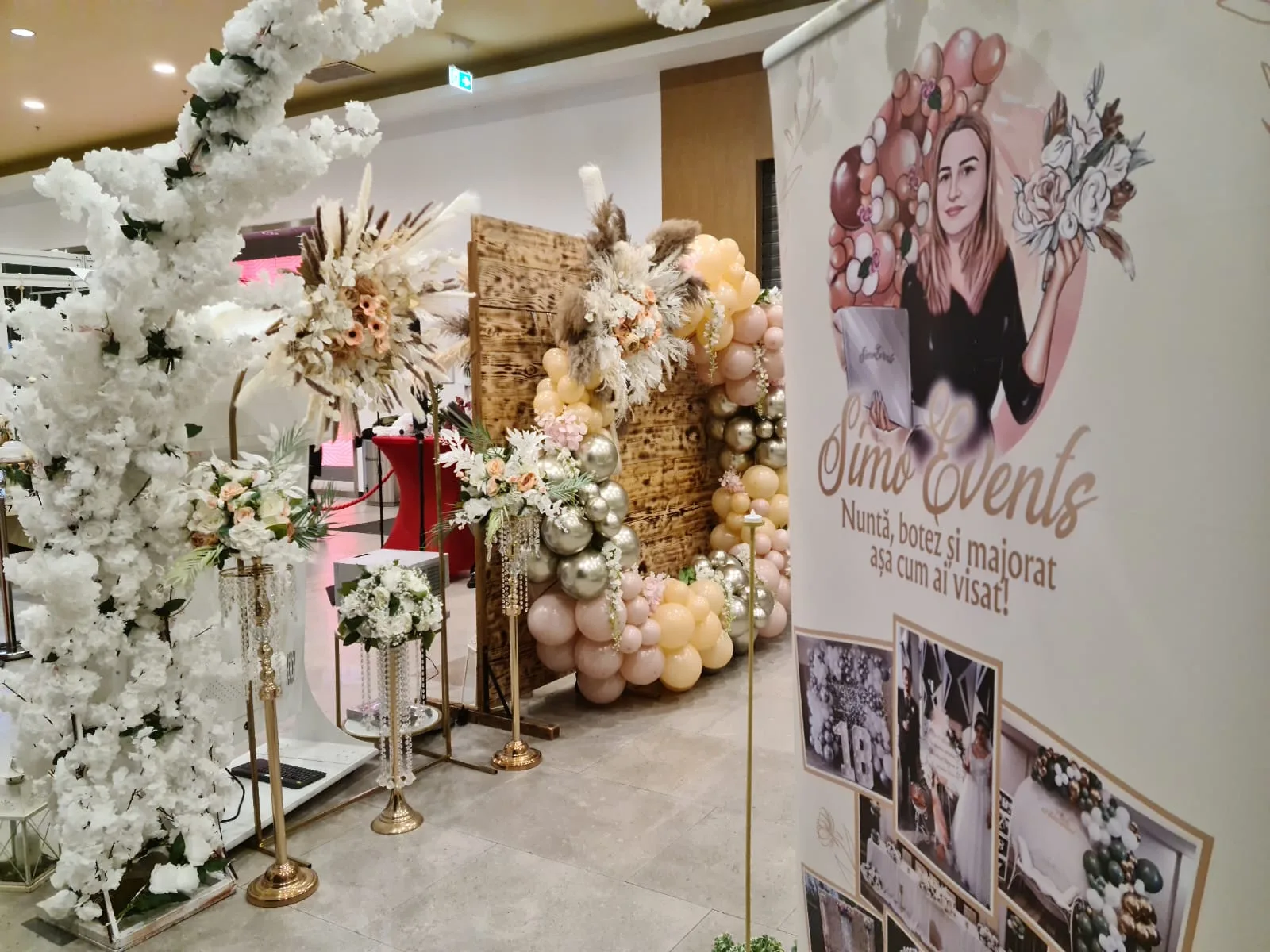 Panou din lemn cu pene si flori, roll-up SimoEvents si arcada de baloane roz-aurii