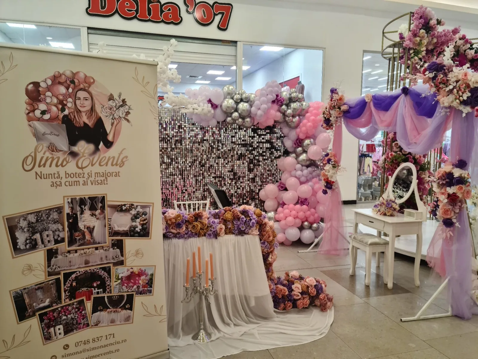 Standul SimoEvents cu banner roll-up si decor floral mov-roz la targul de nunti