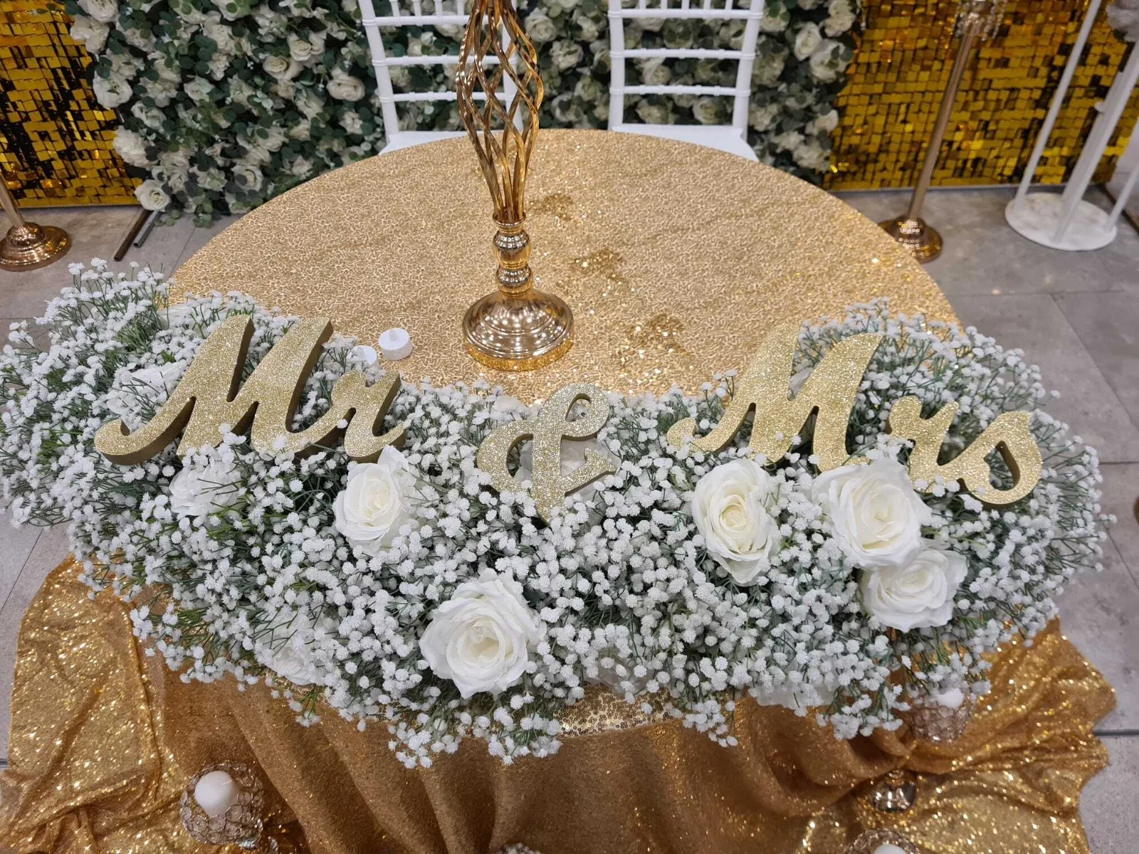 Detaliu masa Mr and Mrs cu gipsofila, trandafiri albi si decor auriu la targul de nunti