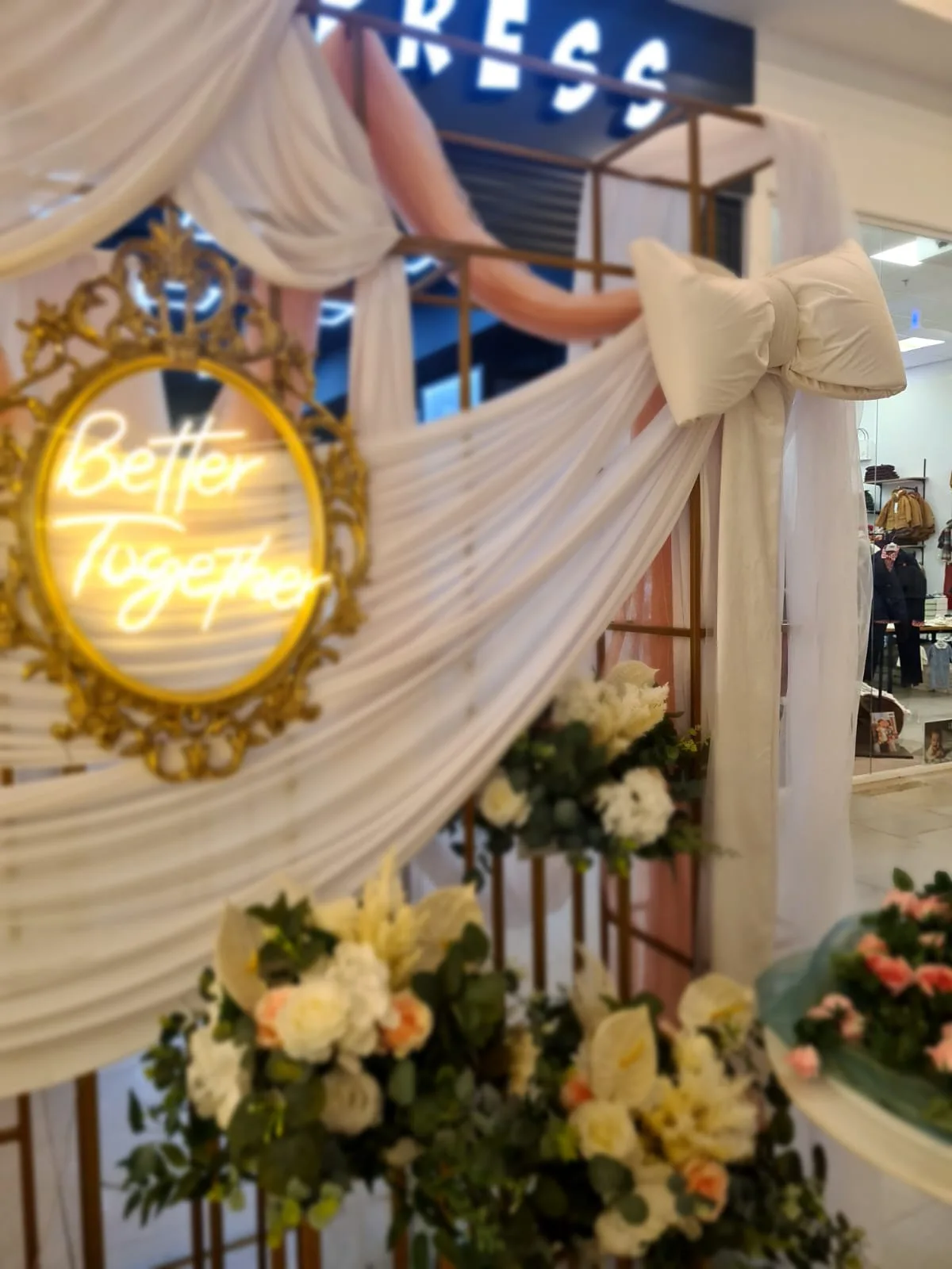 Arcada cu draperie alba, fundita si inscriptia luminoasa Better Together, deasupra unui aranjament floral