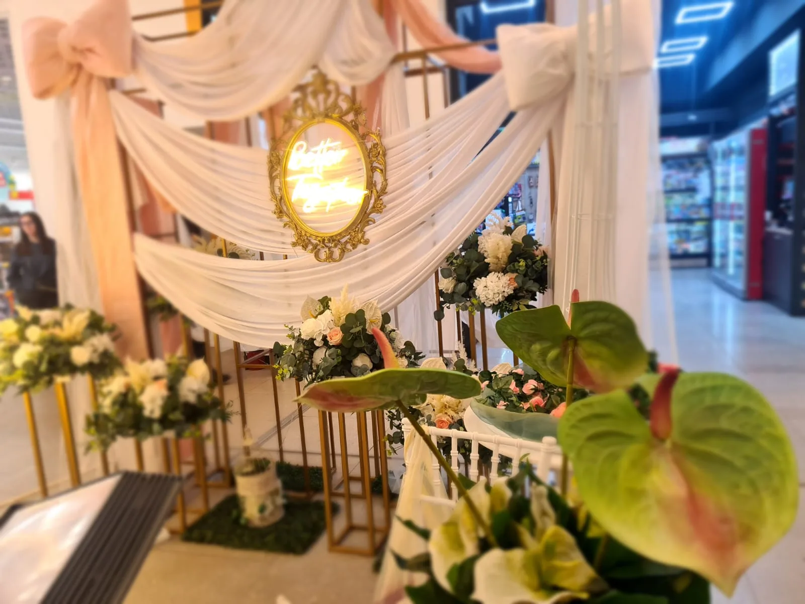 Arcada cu draperie roz, oglinda aurie ovala si flori de anthurium verde pe stative