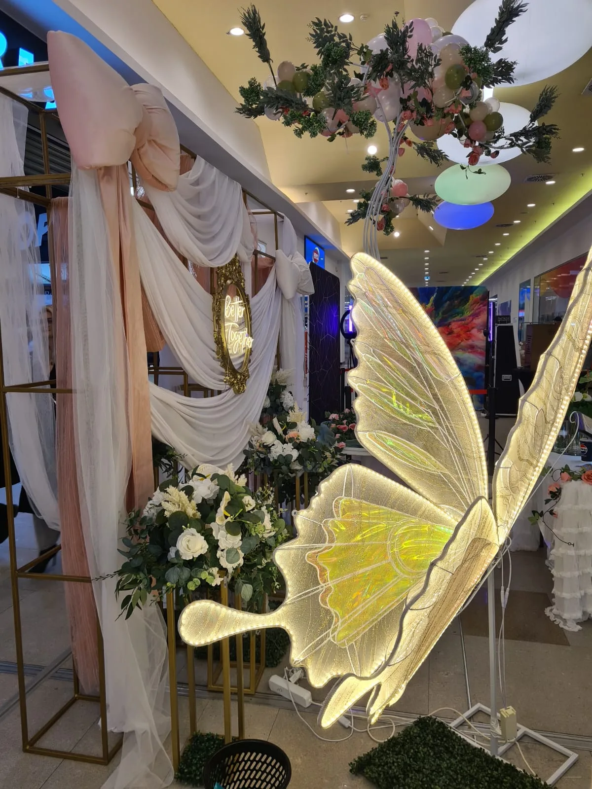 Aripi de fluture luminoase langa arcada cu draperie alba la targul de nunti